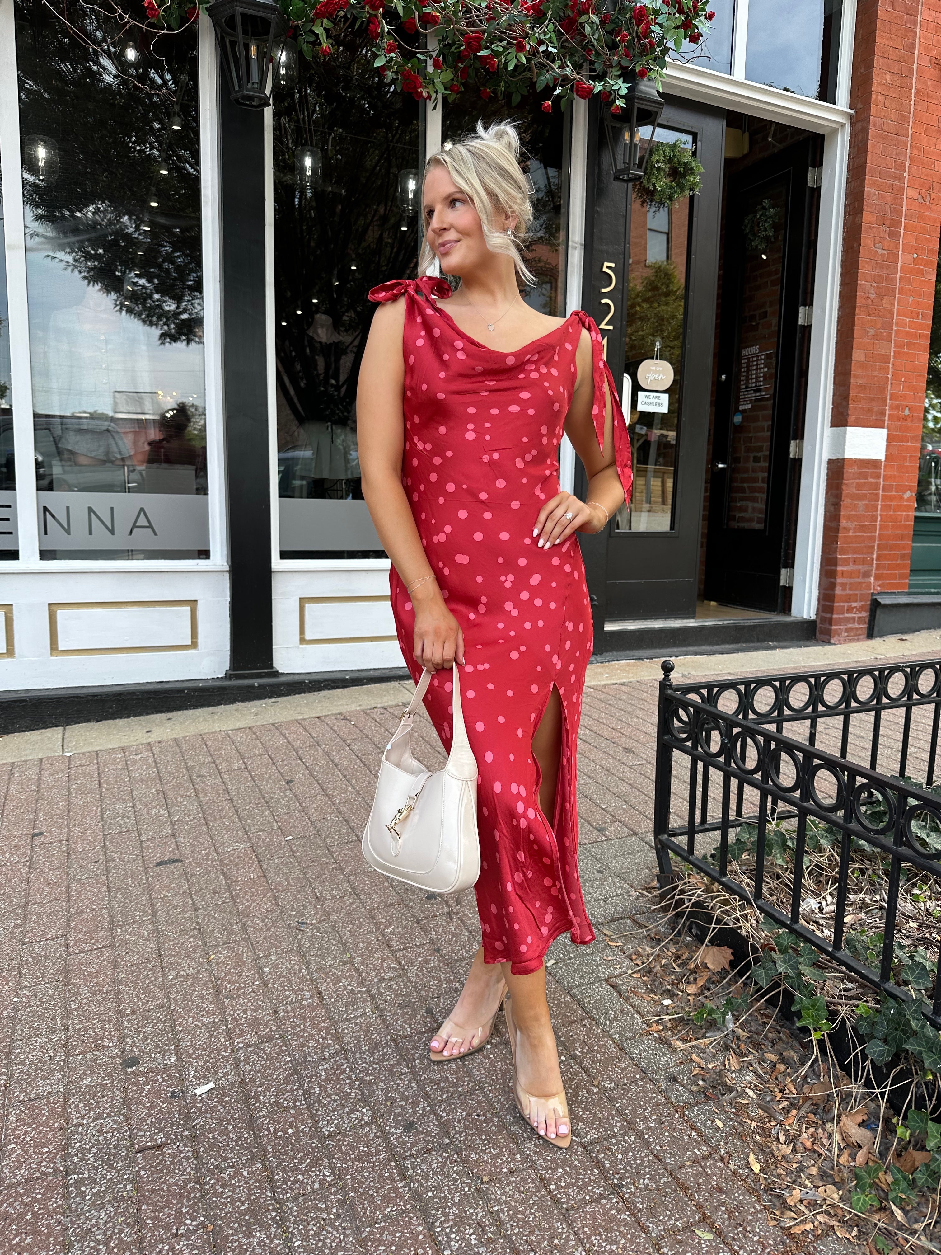 Woman wearing red cowl neck satin midi dress with polka dot pattern. 