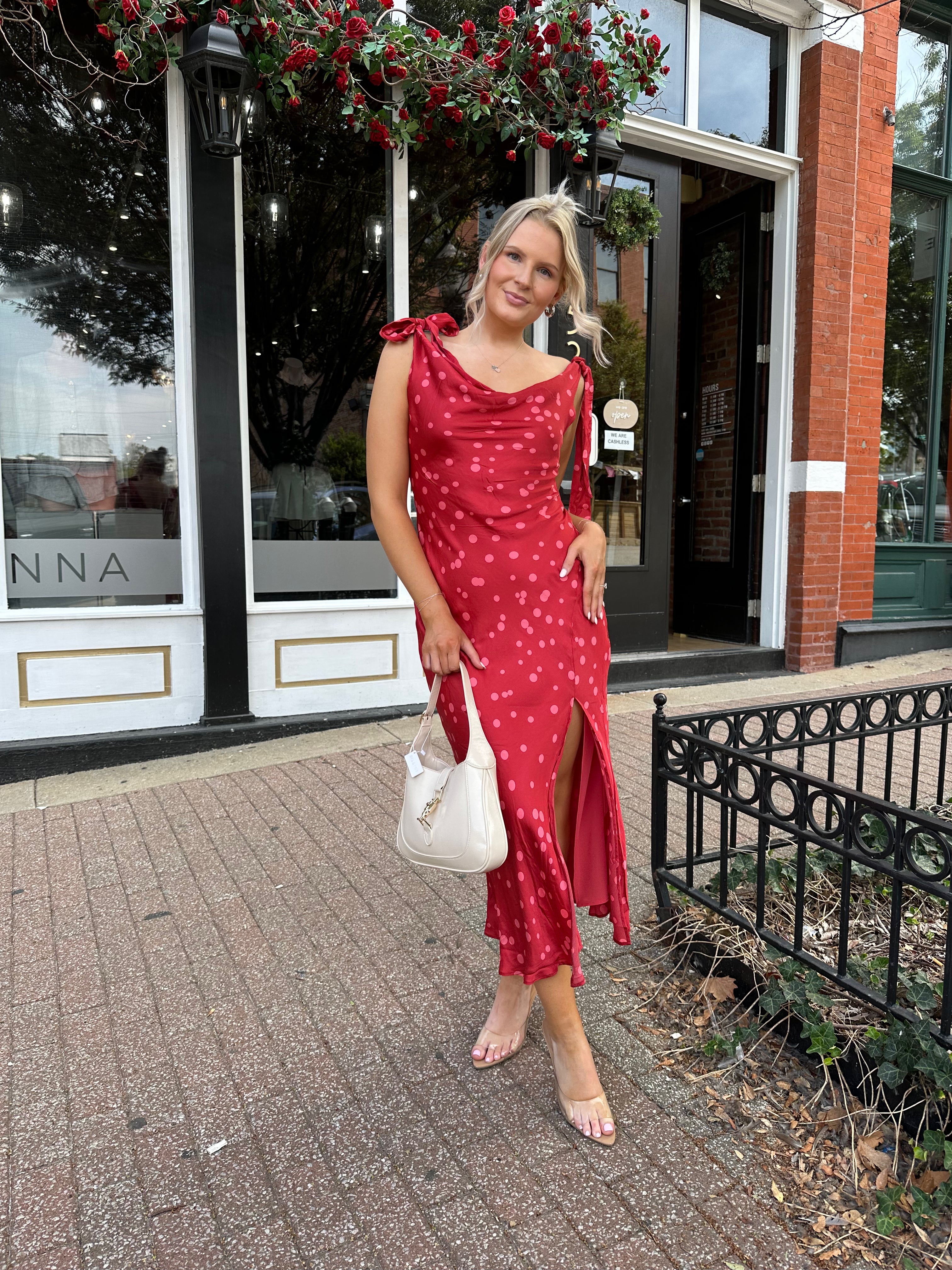 Woman wearing red cowl neck satin midi dress with polka dot pattern. 