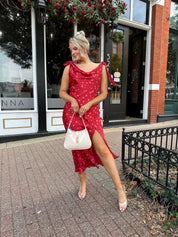 Woman wearing red cowl neck satin midi dress with polka dot pattern. 