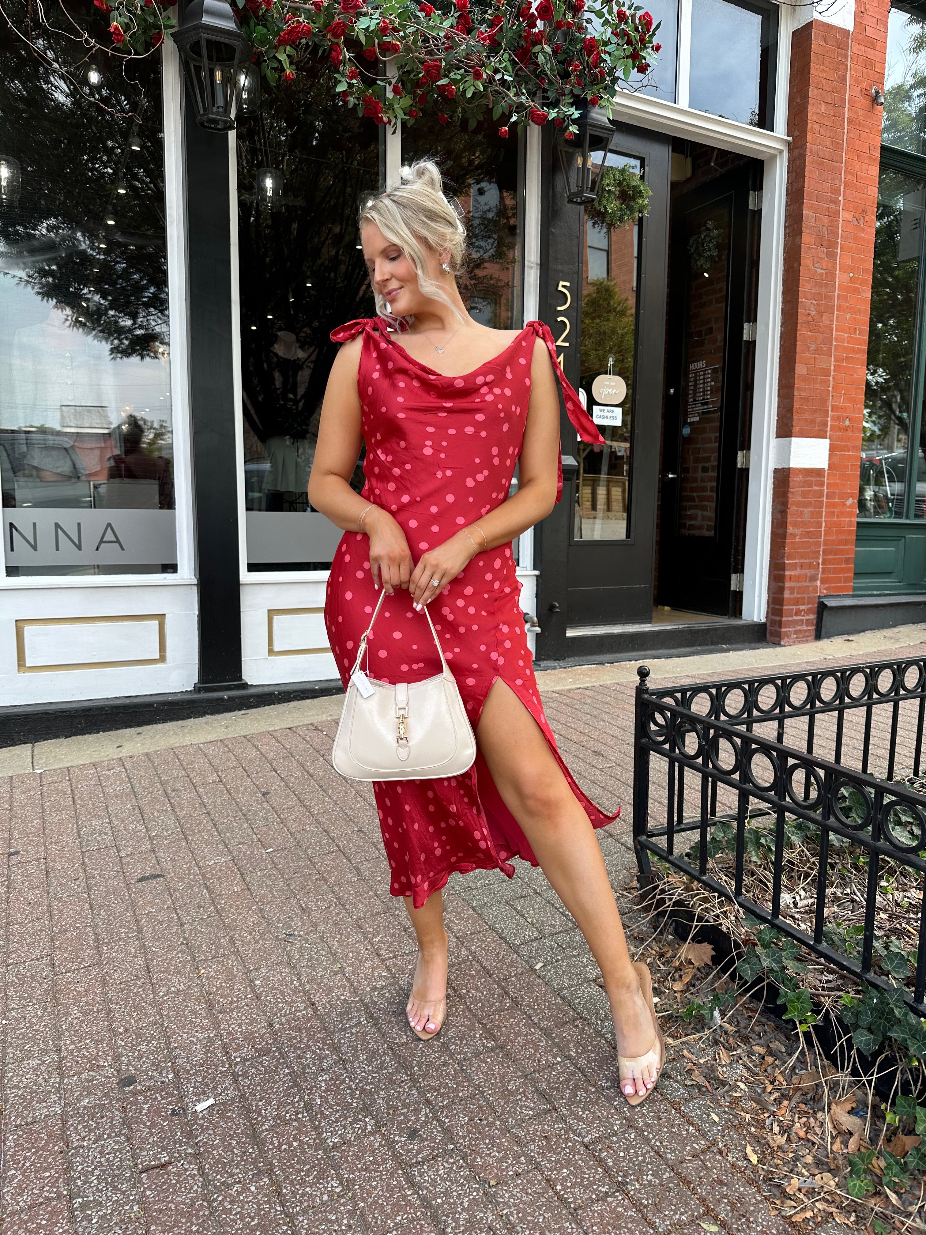 Woman wearing red cowl neck satin midi dress with polka dot pattern. 
