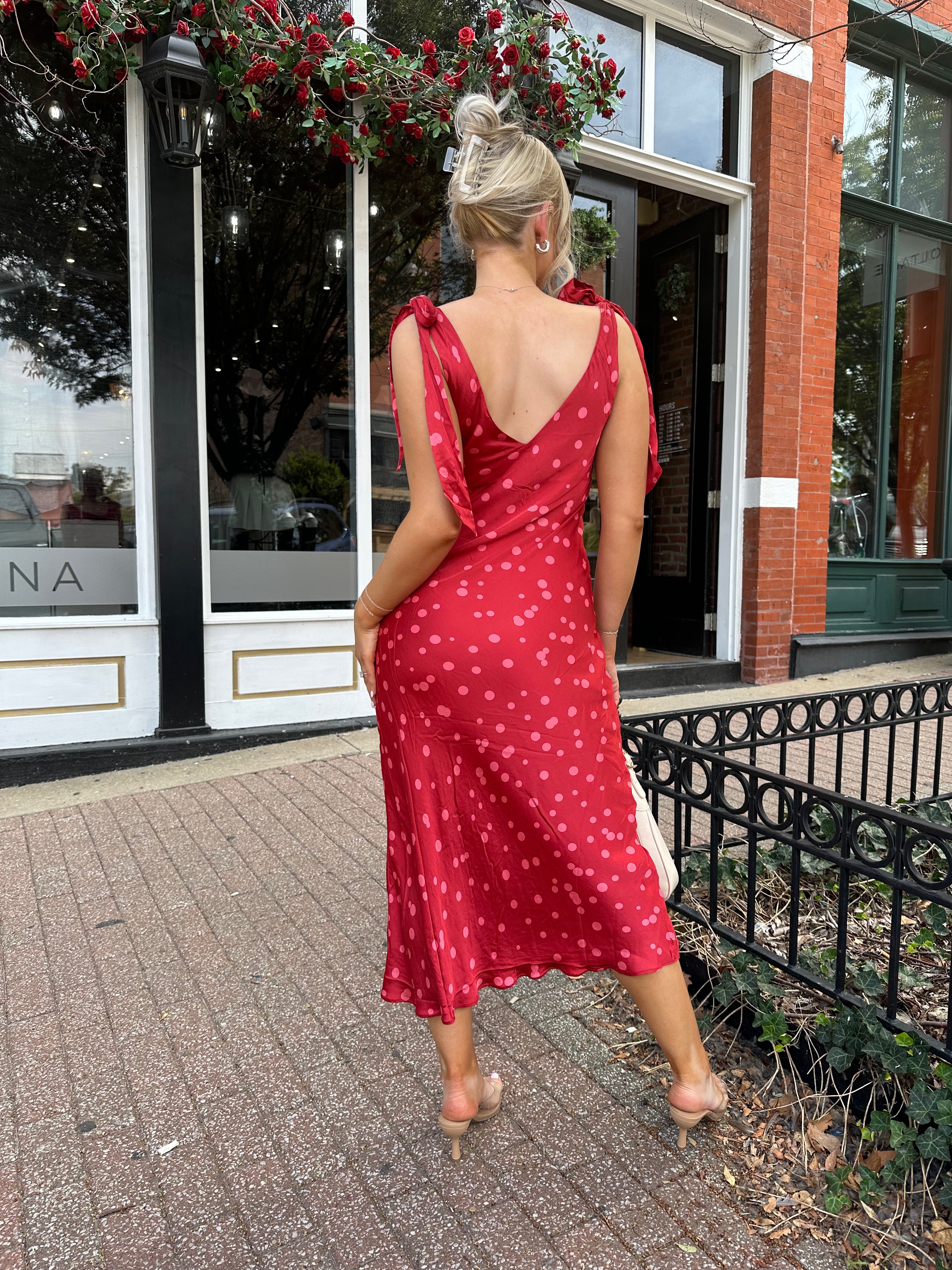 Woman wearing red cowl neck satin midi dress with polka dot pattern. 