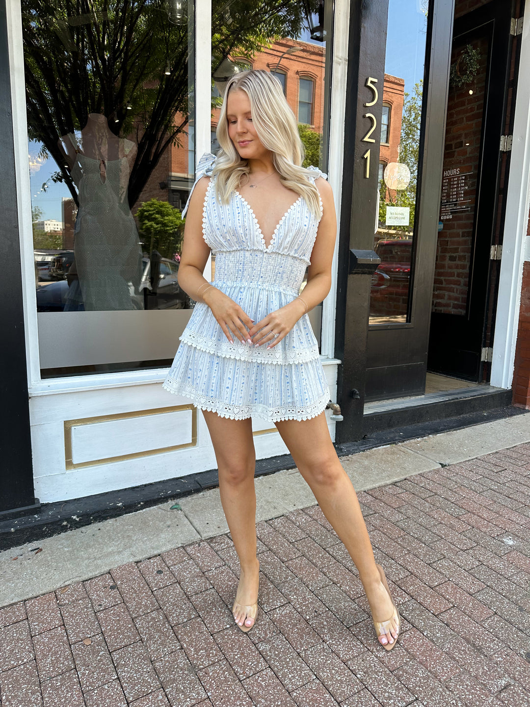 Woman wearing blue floral tiered mini dress with self tie straps, and v-neckline.
