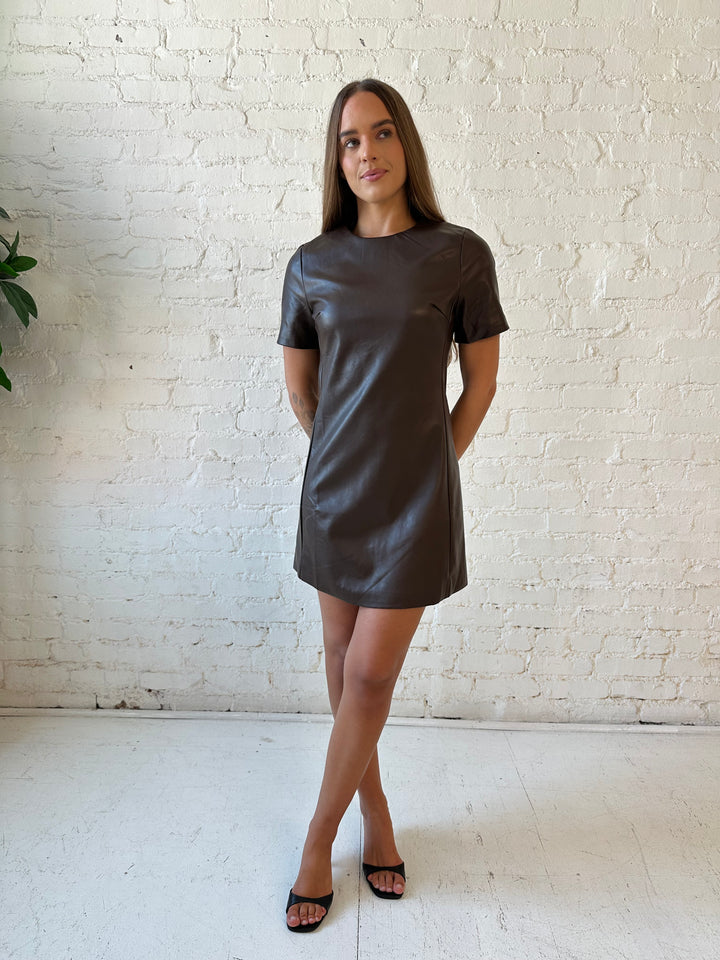Woman wearing brown faux leather short sleeve mini dress with heels. 