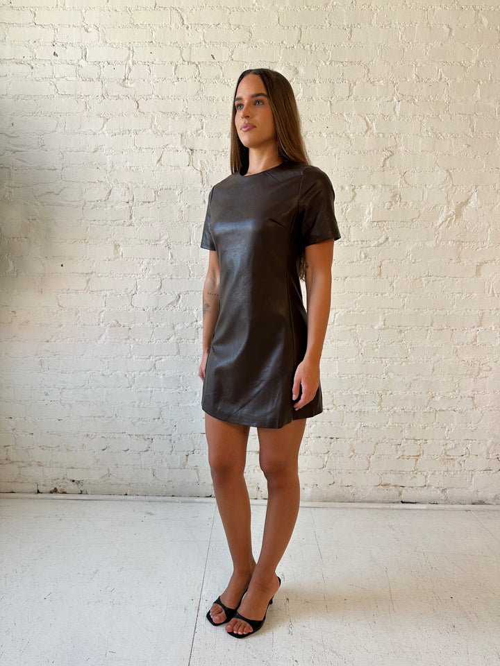 Woman wearing brown faux leather short sleeve mini dress with heels. 