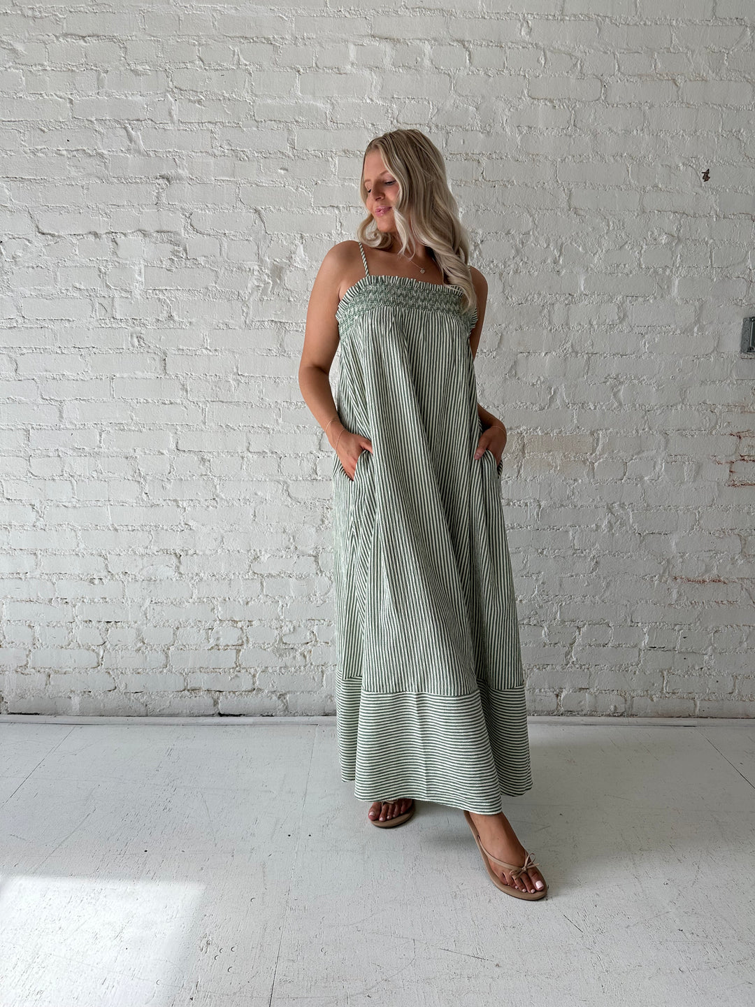 Woman wearing green striped tunic maxi dress with stitch gathering details. 