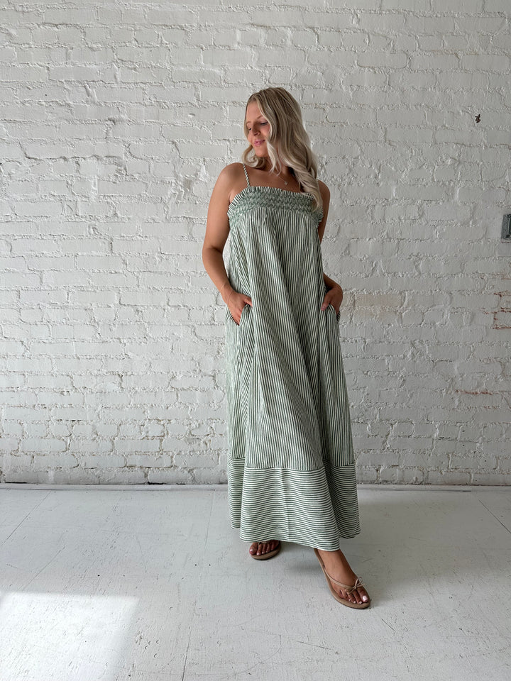 Woman wearing green striped tunic maxi dress with stitch gathering details. 