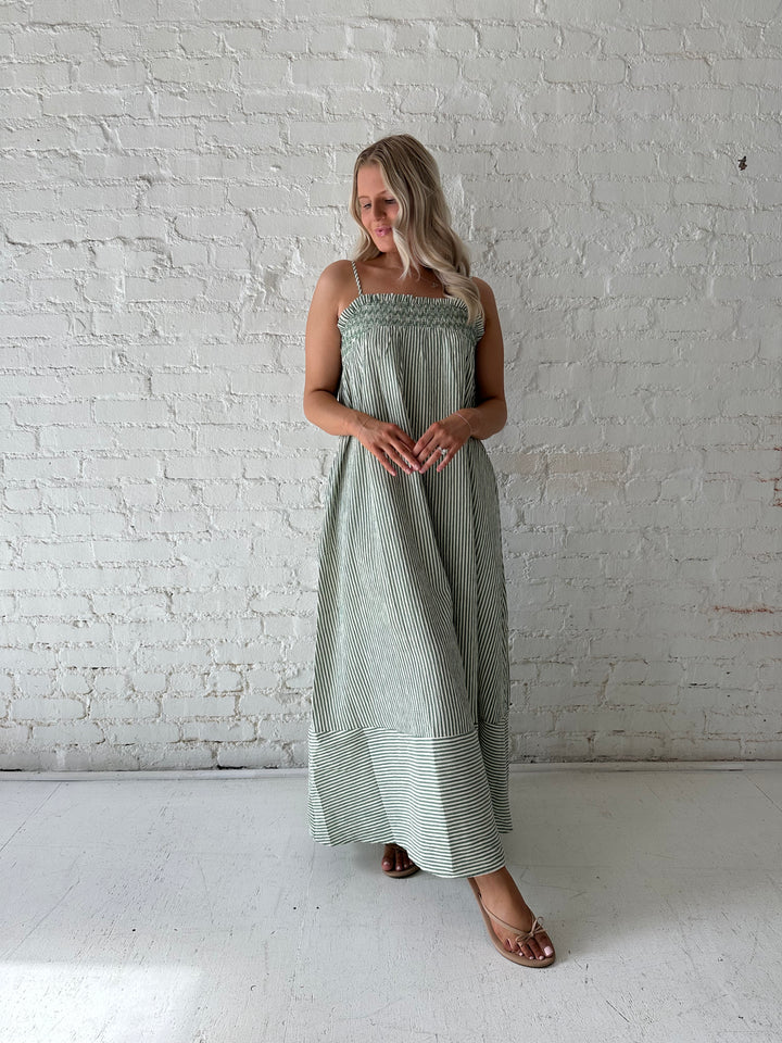 Woman wearing green striped tunic maxi dress with stitch gathering details. 