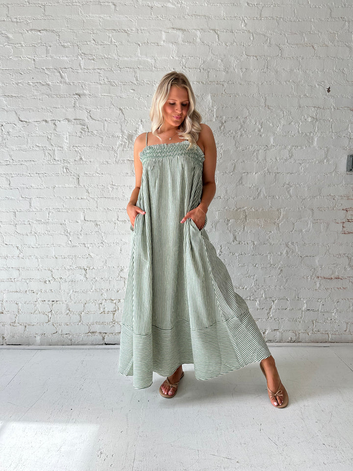 Woman wearing green striped tunic maxi dress with stitch gathering details. 
