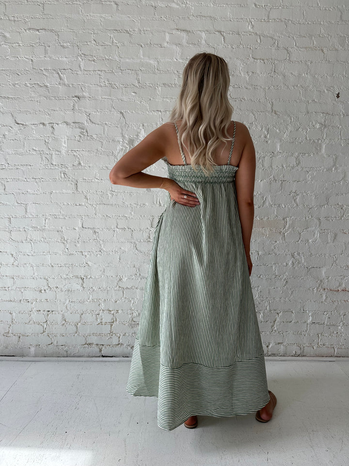 Woman wearing green striped tunic maxi dress with stitch gathering details. 