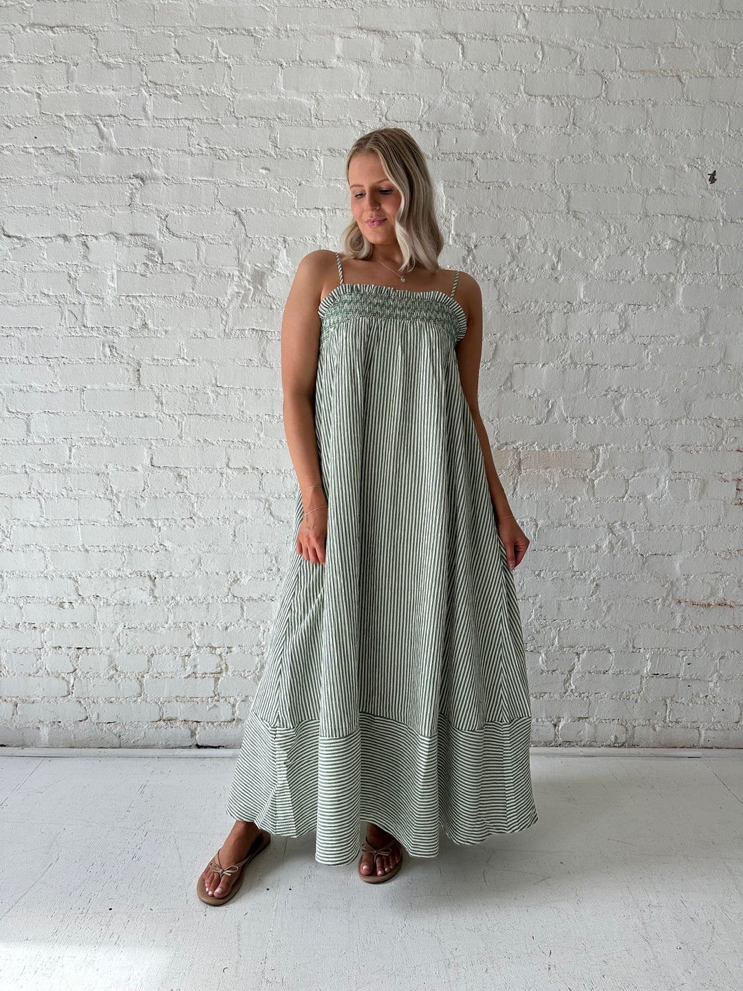 Woman wearing green striped tunic maxi dress with stitch gathering details. 