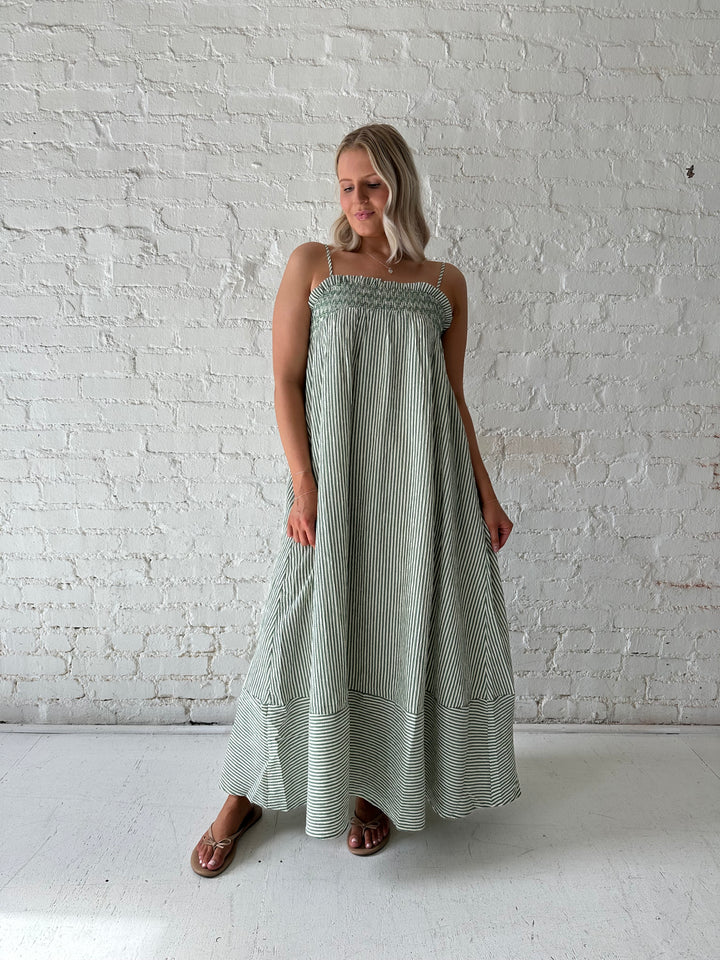 Woman wearing green striped tunic maxi dress with stitch gathering details. 