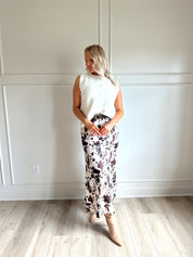 Woman wearing satin cow print maxi skirt with belt detail and white sweater top.