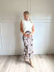Woman wearing satin cow print maxi skirt with belt detail and white sweater top.