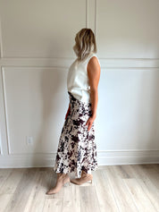 Woman wearing satin cow print maxi skirt with belt detail and white sweater top.