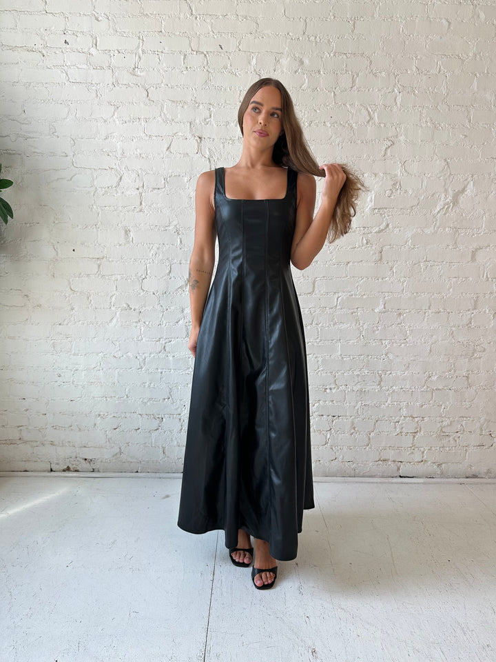 Woman wearing black faux leather flowy maxi dress with black heel.