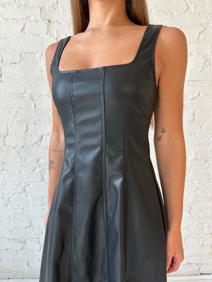 Woman wearing black faux leather flowy maxi dress with black heel.