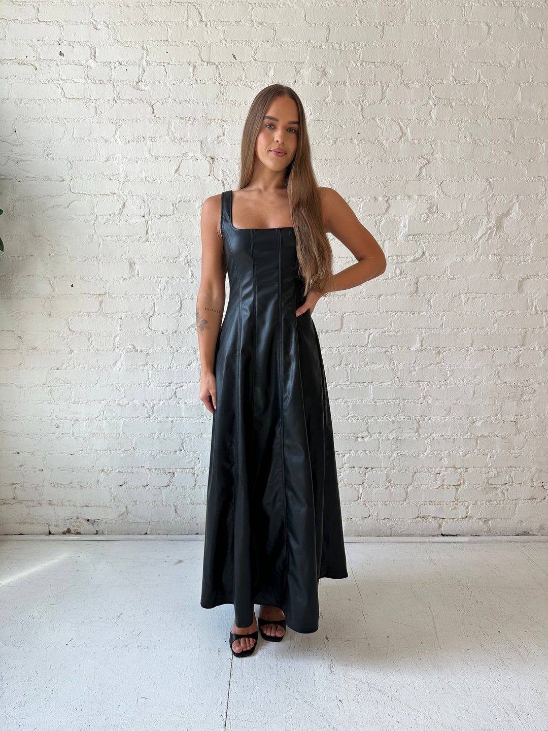 Woman wearing black faux leather flowy maxi dress with black heel.