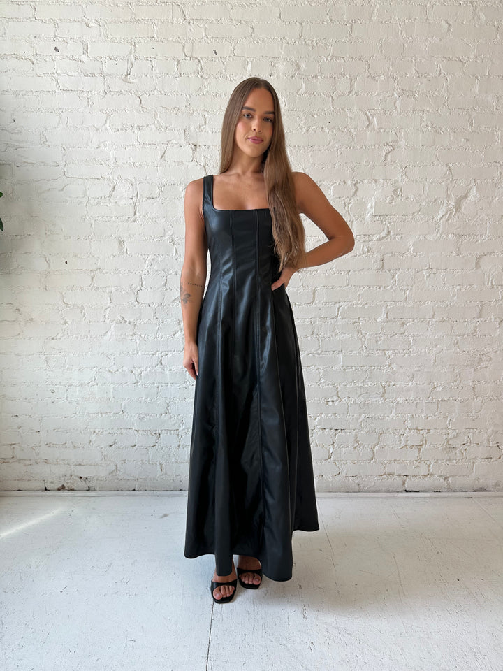 Woman wearing black faux leather flowy maxi dress with black heel.