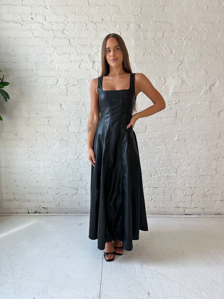 Woman wearing black faux leather flowy maxi dress with black heel.