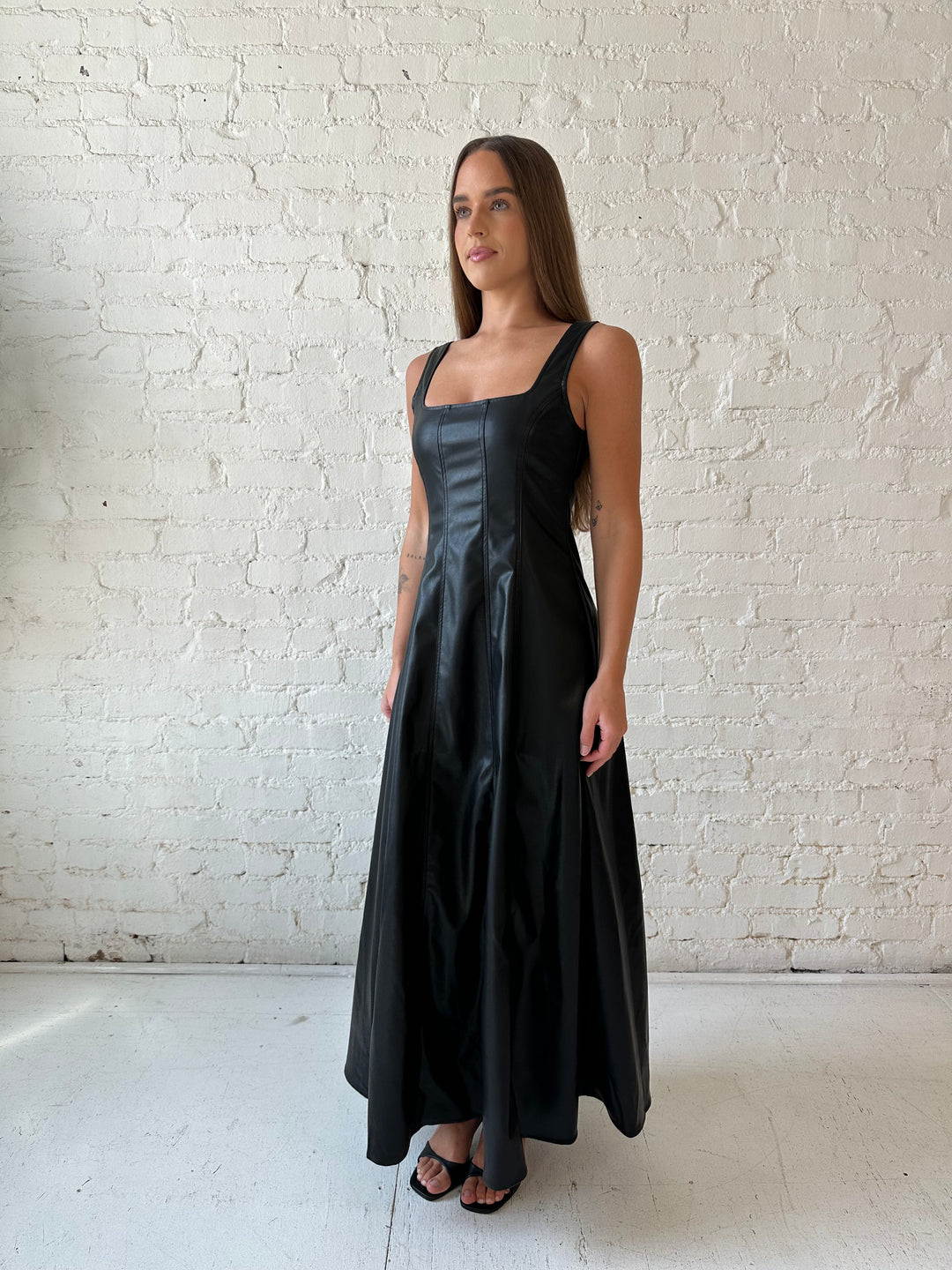 Woman wearing black faux leather flowy maxi dress with black heel.