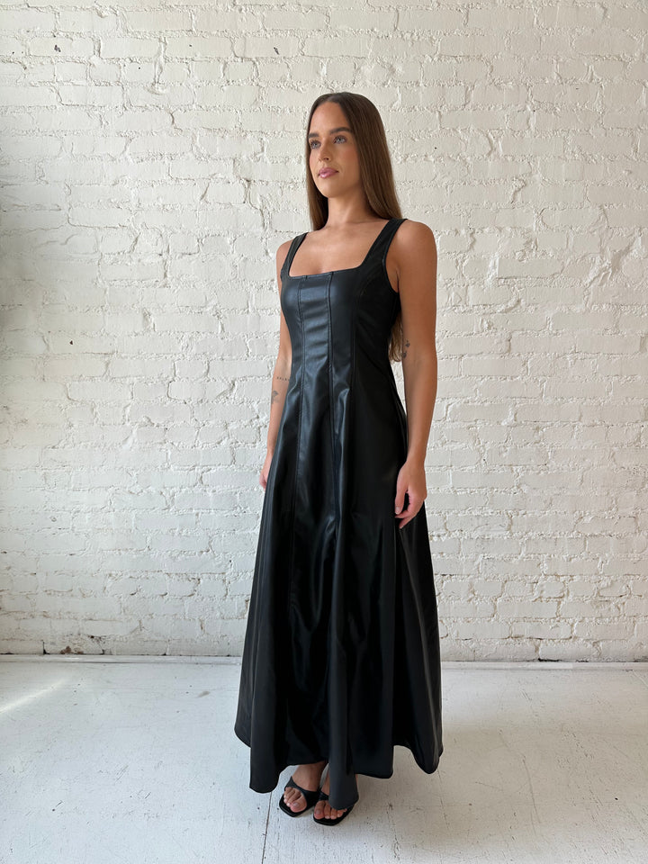 Woman wearing black faux leather flowy maxi dress with black heel.