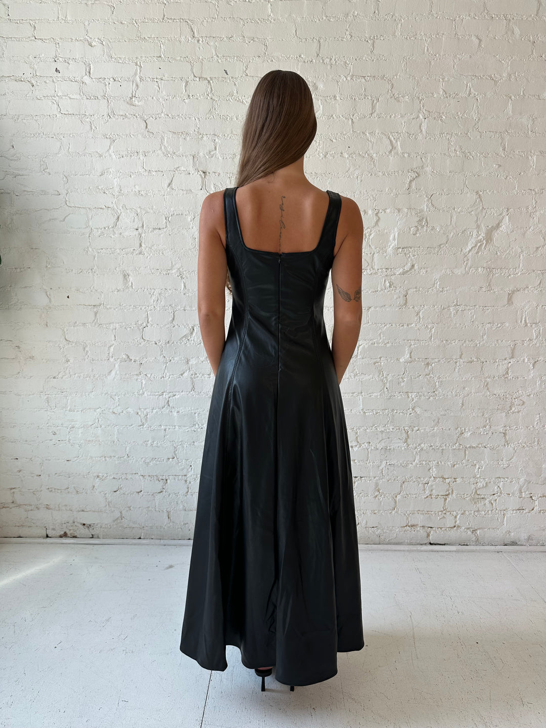 Woman wearing black faux leather flowy maxi dress with black heel.