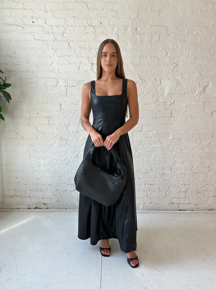 Woman wearing black faux leather flowy maxi dress with black heel.
