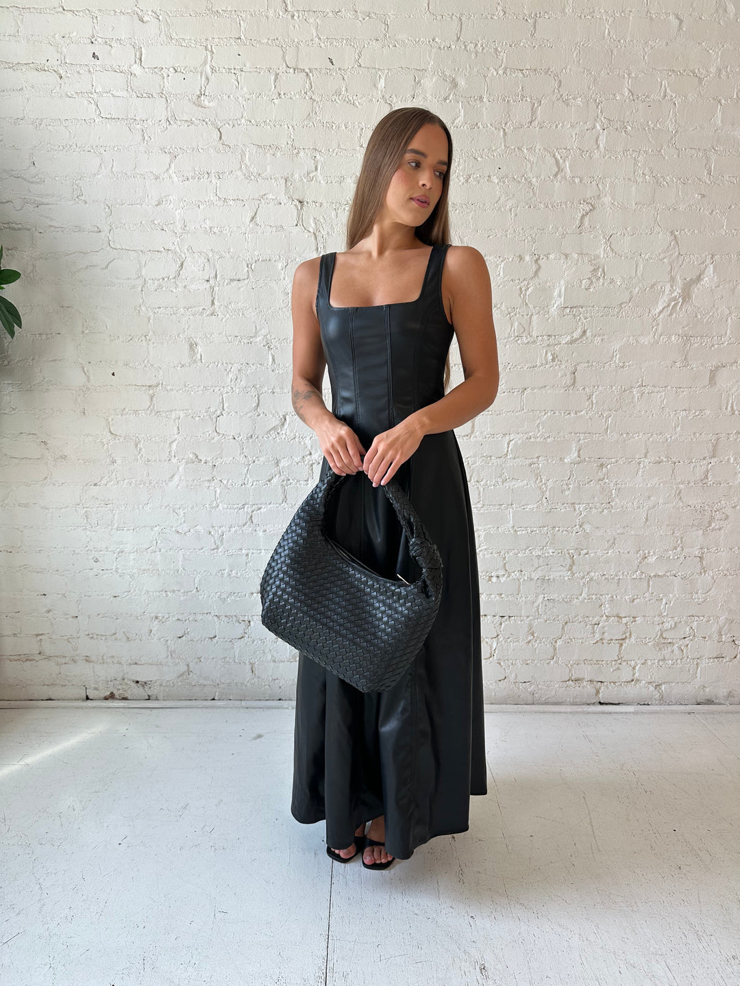 Woman wearing black faux leather flowy maxi dress with black heel.