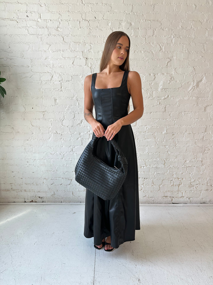 Woman wearing black faux leather flowy maxi dress with black heel.
