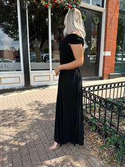 Woman wearing a black one shoulder maxi dress with flowy bottom.