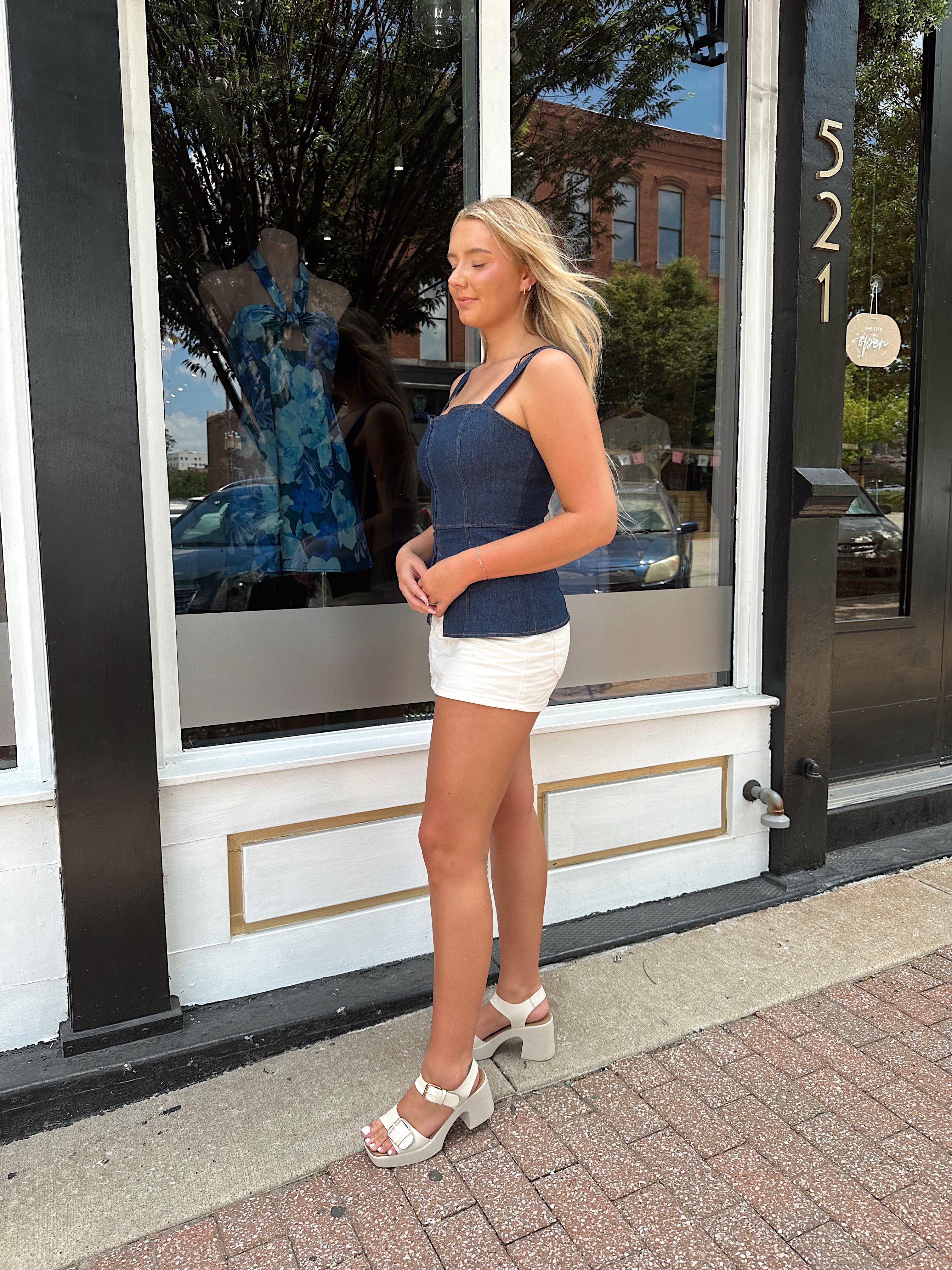 Dark wash denim peplum corset top with clasp closure.