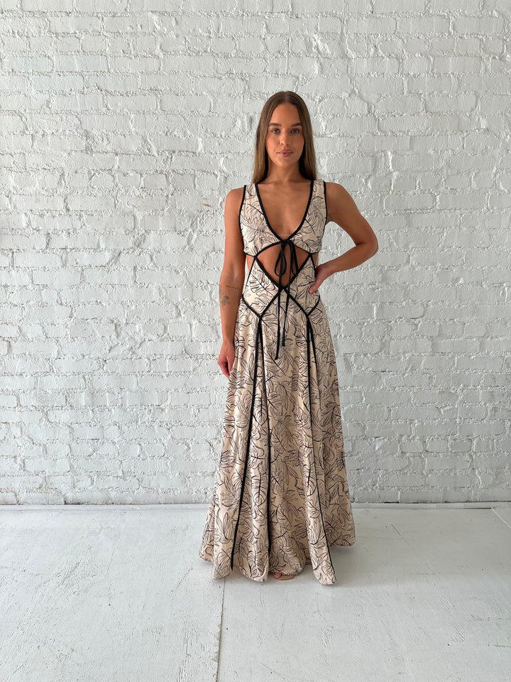 Woman wearing beige floral maxi dress with cutout midsection, and cutout sides. 