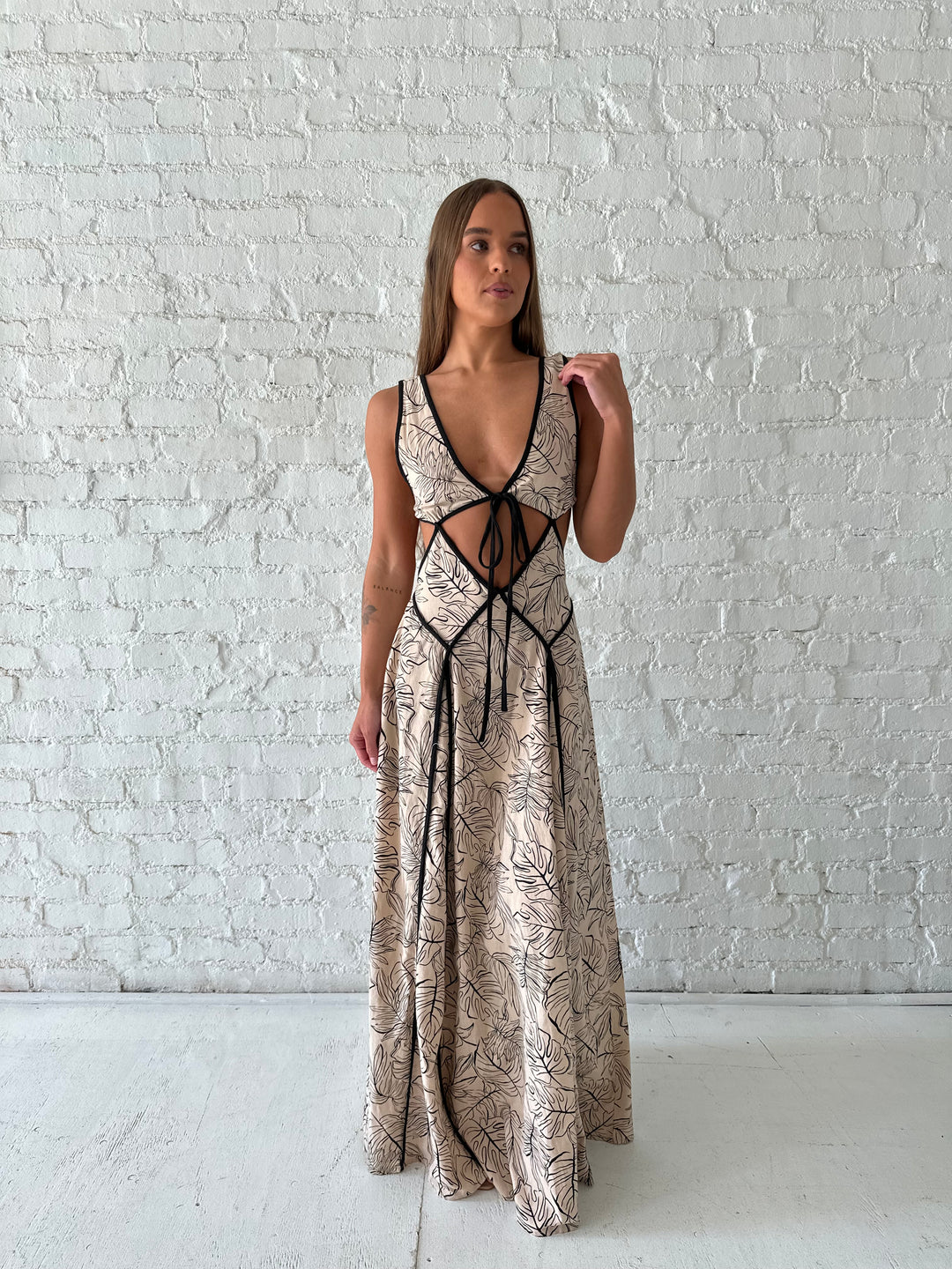 Woman wearing beige floral maxi dress with cutout midsection, and cutout sides. 