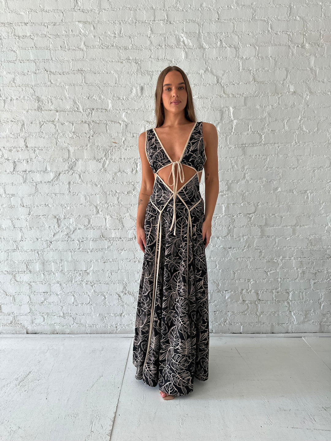 Woman wearing beige  and black floral maxi dress with cutout midsection, and cutout sides. 