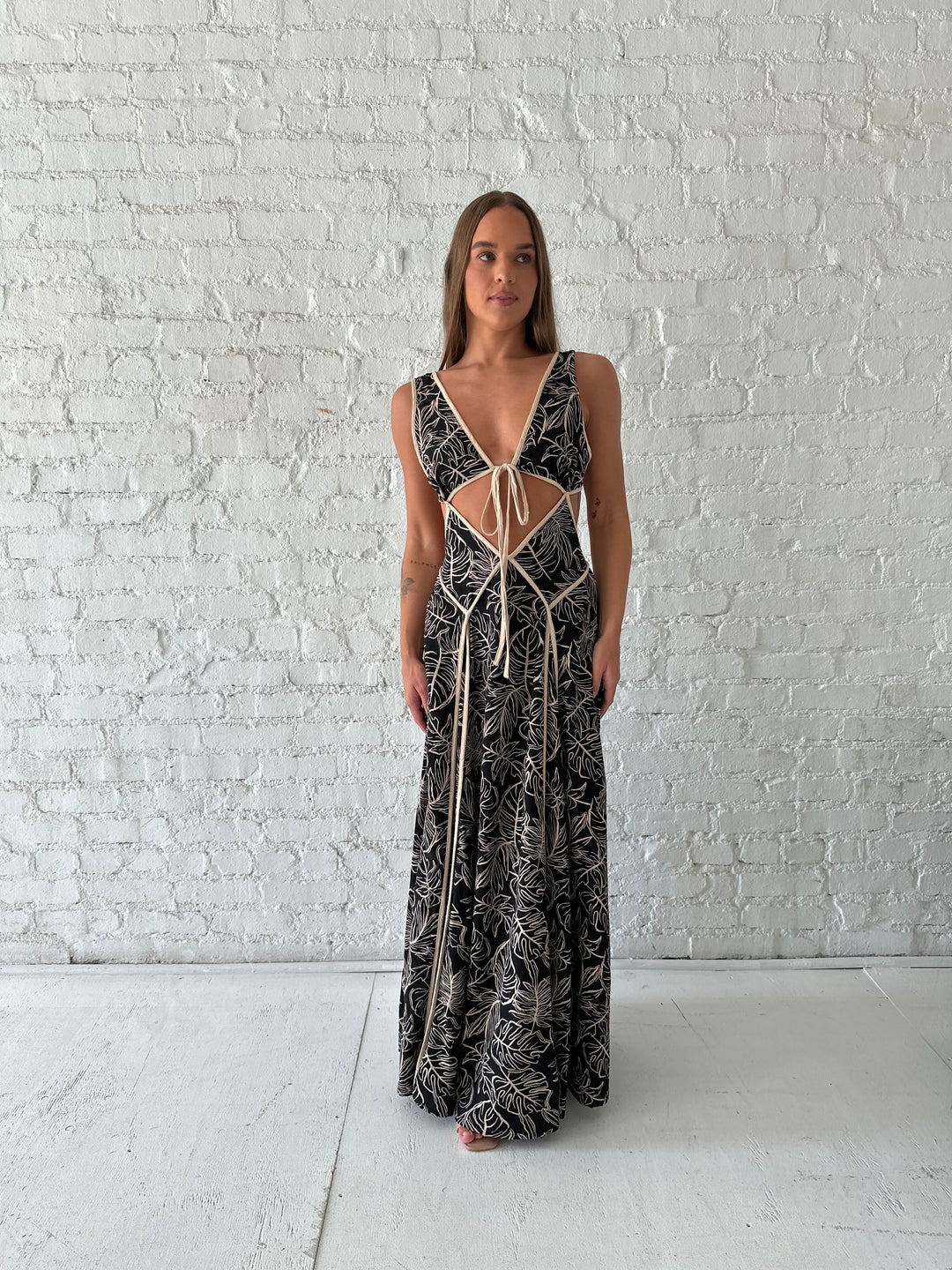 Woman wearing beige  and black floral maxi dress with cutout midsection, and cutout sides. 