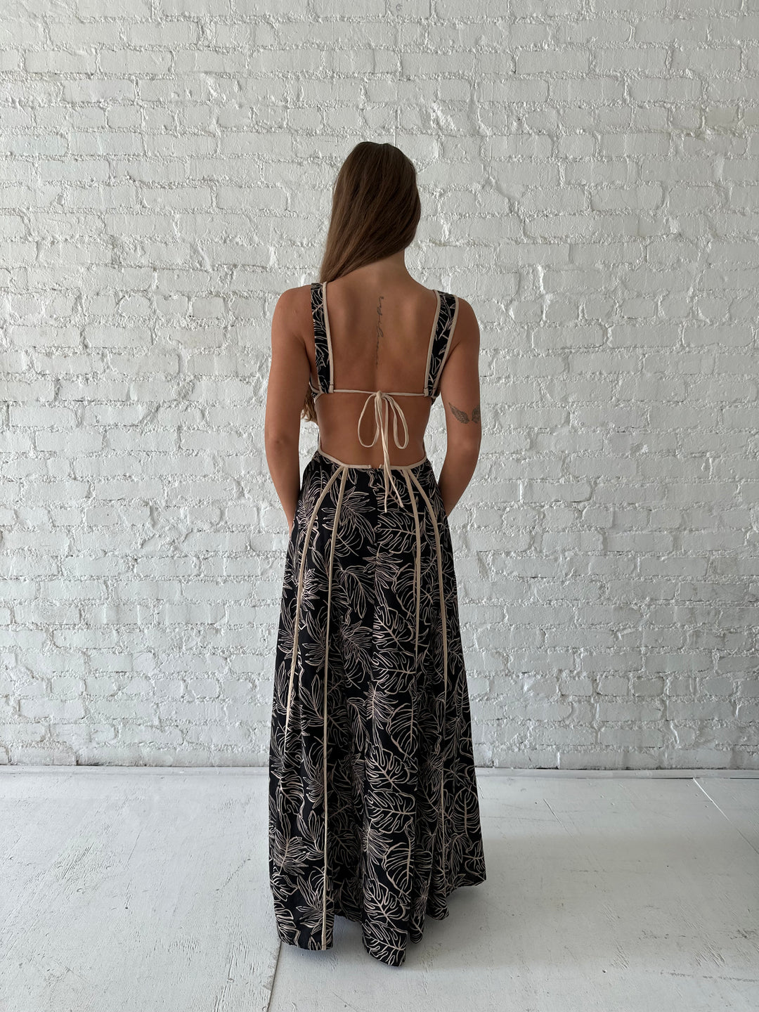Woman wearing beige  and black floral maxi dress with cutout midsection, and cutout sides. 