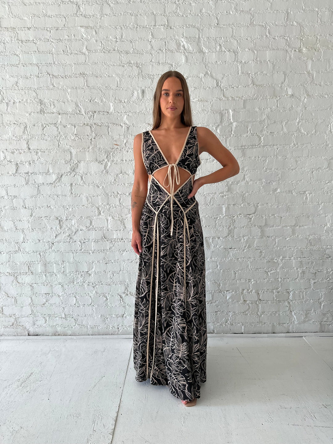 Woman wearing beige  and black floral maxi dress with cutout midsection, and cutout sides. 