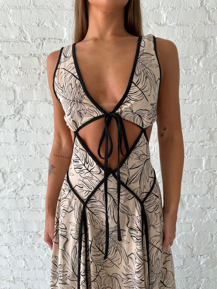 Woman wearing beige floral maxi dress with cutout midsection, and cutout sides. 