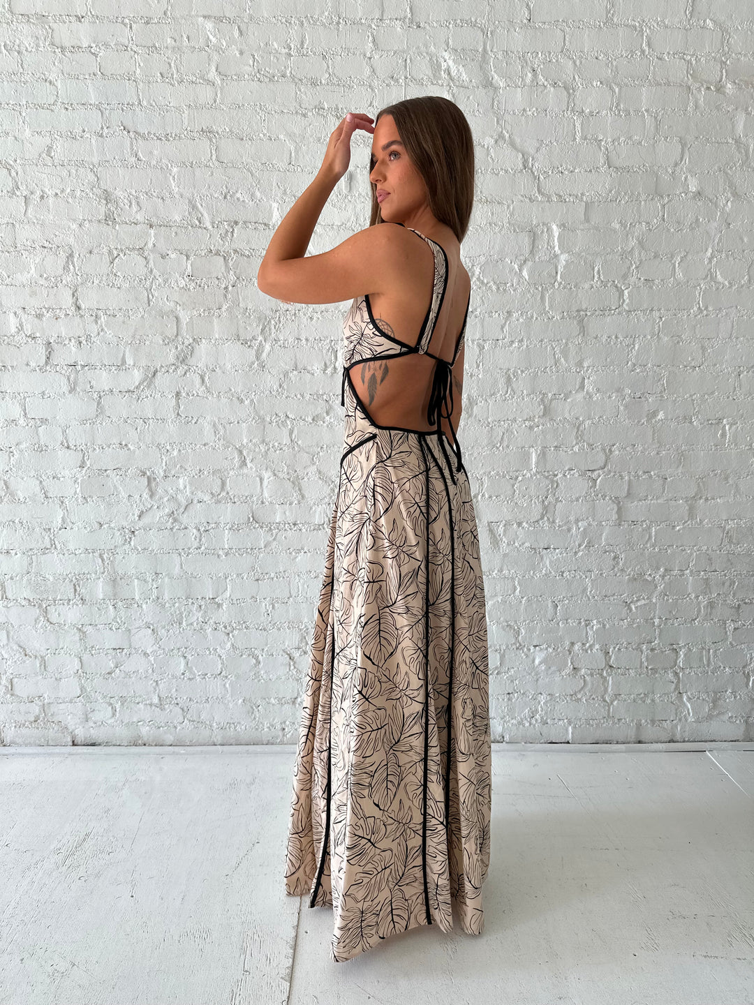 Woman wearing beige floral maxi dress with cutout midsection, and cutout sides. 
