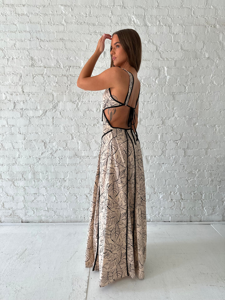 Woman wearing beige floral maxi dress with cutout midsection, and cutout sides. 