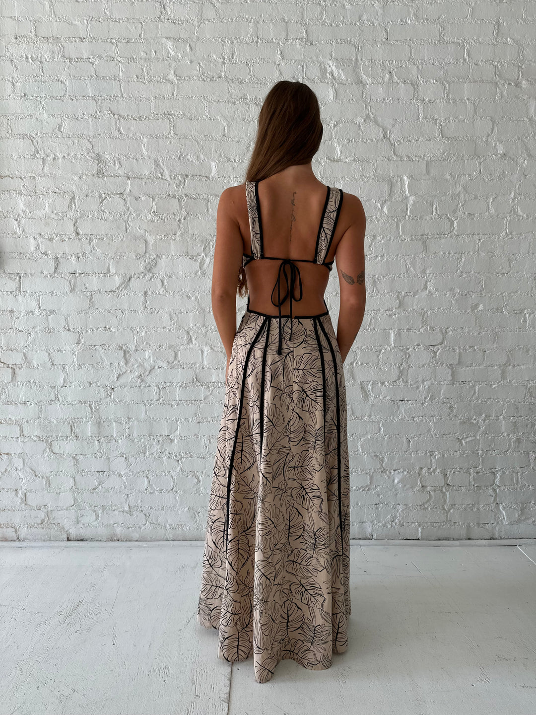 Woman wearing beige floral maxi dress with cutout midsection, and cutout sides. 