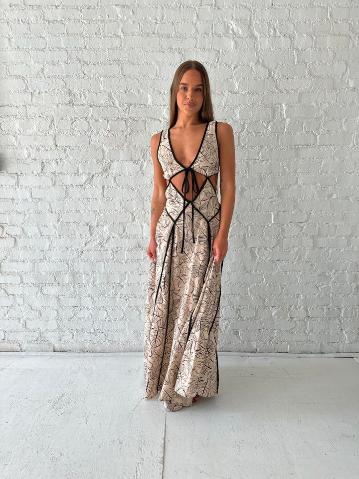 Woman wearing beige floral maxi dress with cutout midsection, and cutout sides. 