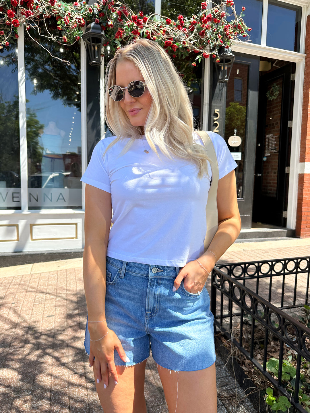 Woman wearing white relaxed t-shirt with denim shorts.
