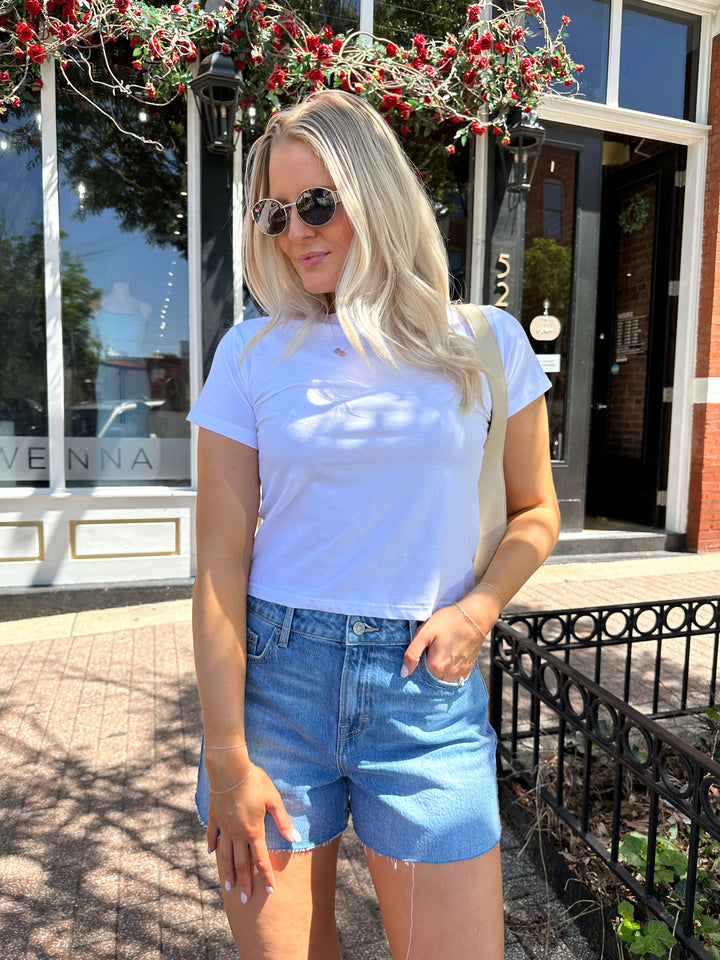 Woman wearing white relaxed t-shirt with denim shorts.