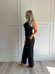 Woman wearing black two piece set with cowl neck top, and tailored wide leg pant.