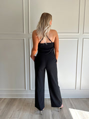 Woman wearing black two piece set with cowl neck top, and tailored wide leg pant.