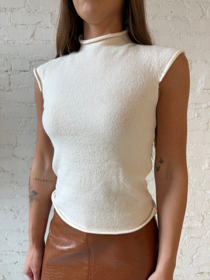 Woman wearing cream knit cap sleeve top and cognac leather mini skirt. 