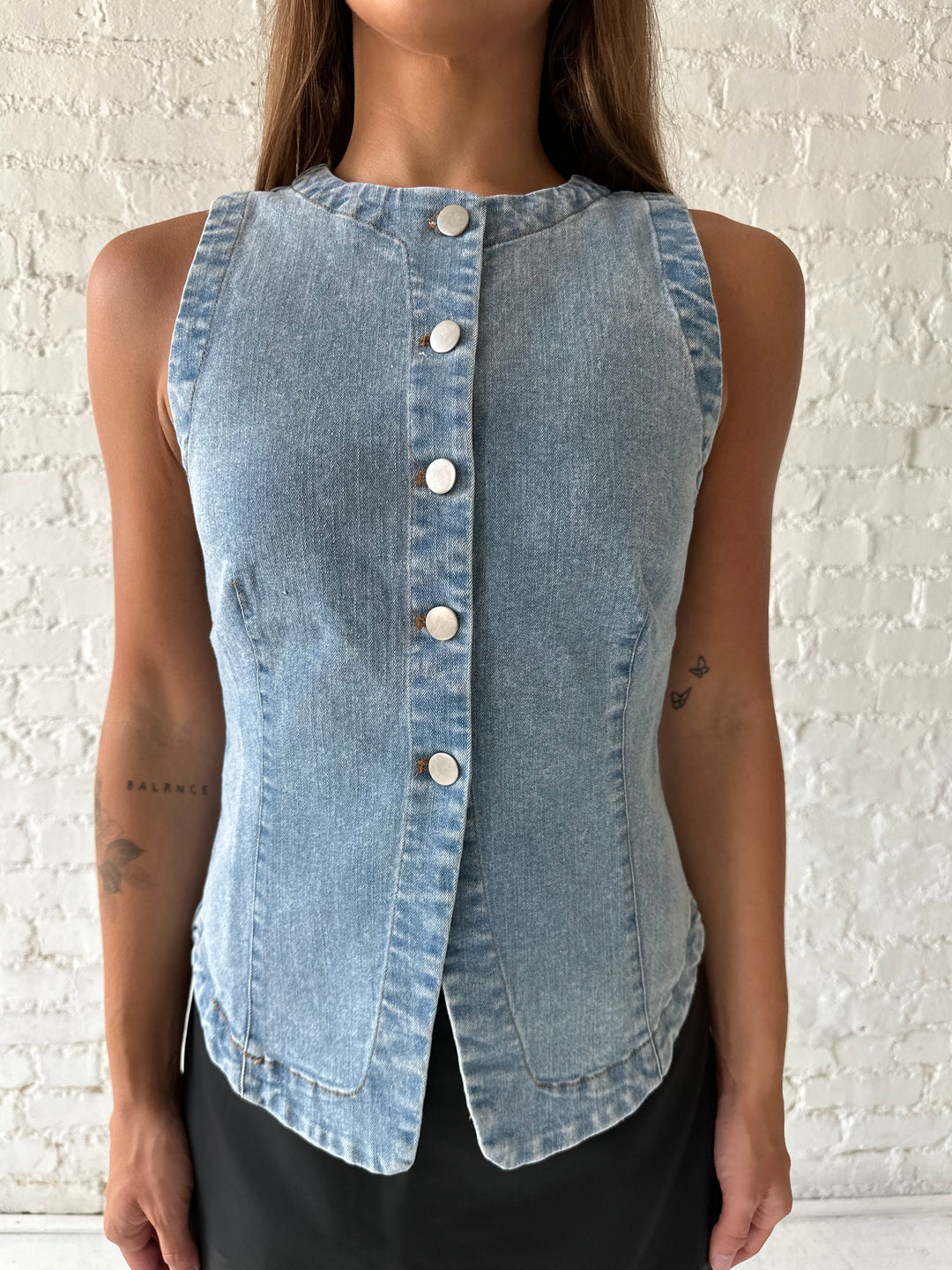 Woman wearing denim button down top with black leather mini skort. 