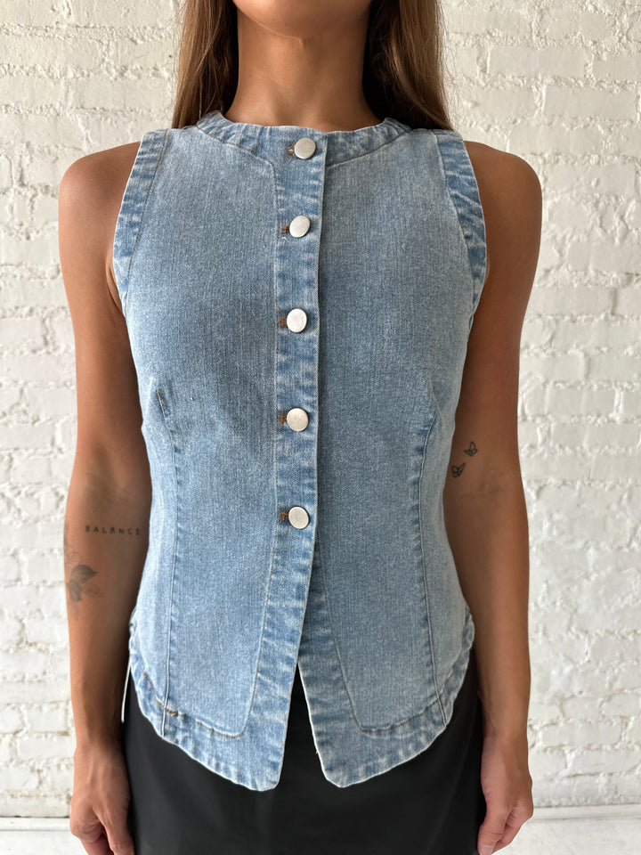 Woman wearing denim button down top with black leather mini skort. 