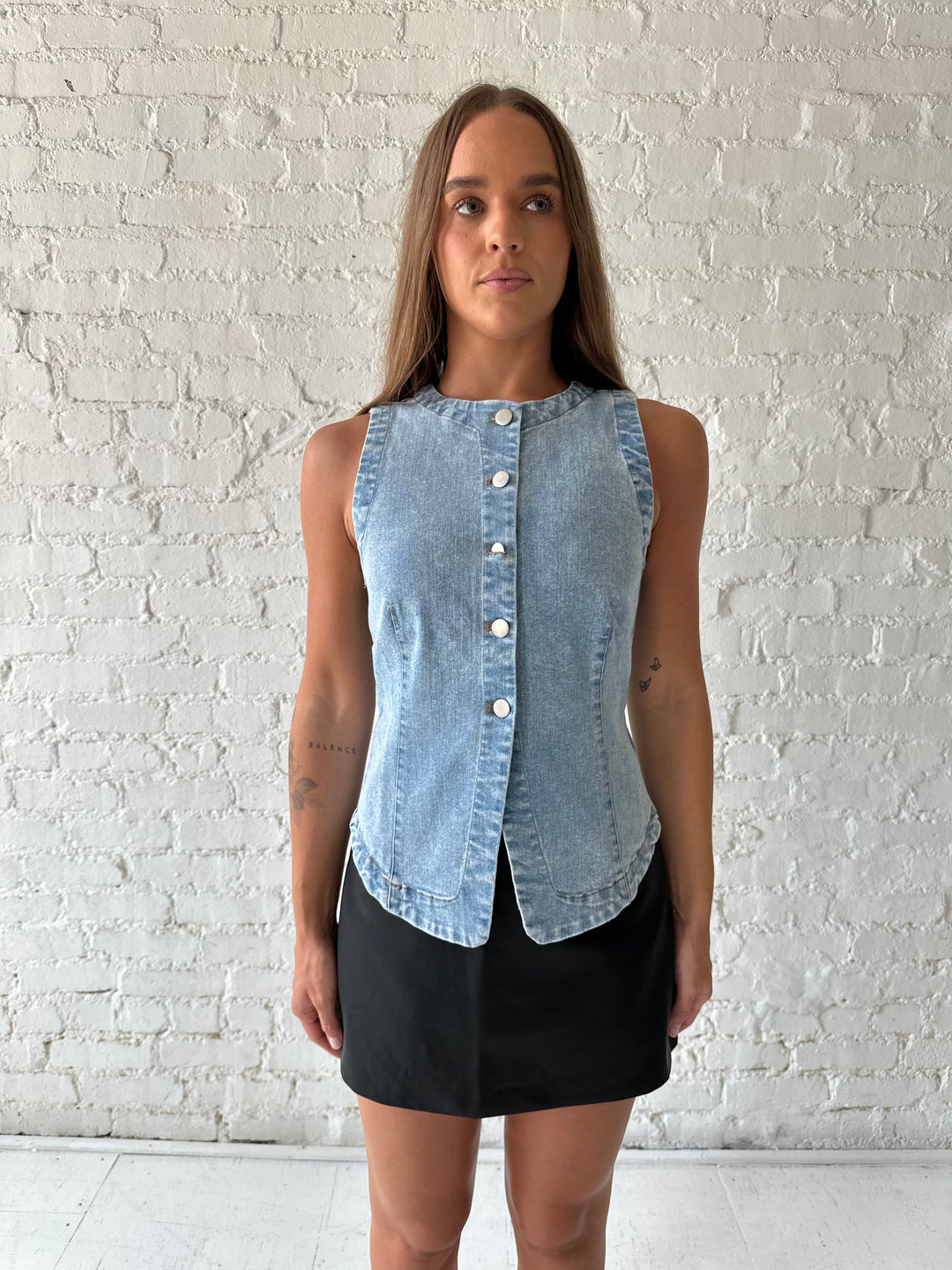 Woman wearing denim button down top with black leather mini skort. 